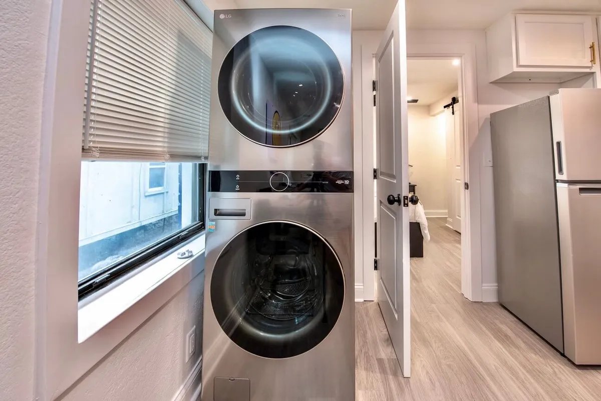 A practical laundry area equipped with a stacked washer and dryer sits next to a window, filling the space with natural light. The setup is functional and streamlined, suggesting efficiency and convenience for everyday living.